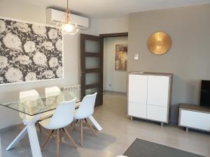 a dining room with a glass table and white chairs at Apartamentos Real Lleida in Lleida