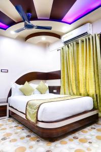 a bedroom with a bed in a room with yellow curtains at Hotel Bangabhumi in Alīpur Duār