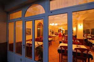 a woman standing in front of a restaurant with tables at Hotel Stanger in Lovran