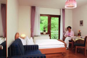 Eine Frau auf einem Bett in einem Hotelzimmer in der Unterkunft Pension Burk in Bad Endbach