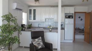 a kitchen with white cabinets and a chair in a room at Sa Maniga 6 O Apartment Stephanie in Cala Millor