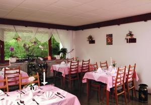ein Esszimmer mit Tischen, Stühlen und rosa Tischdecken in der Unterkunft Pension Burk in Bad Endbach