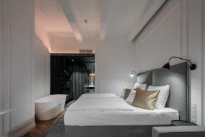 a bedroom with a tub and a bed and a sink at Pytloun Boutique Hotel Prague in Prague