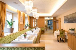 a restaurant with white tables and chairs and chandeliers at Hotel Steirerrast in Kaindorf