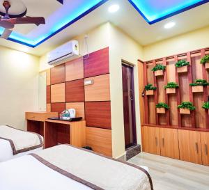 ein Hotelzimmer mit 2 Betten und einem TV in der Unterkunft Hotel Bangabhumi in Alīpur Duār