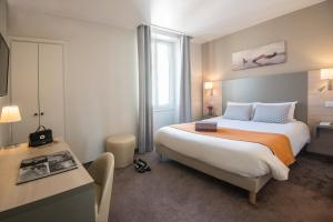 ein Hotelzimmer mit einem großen Bett und einem Schreibtisch in der Unterkunft Hotel Du Midi in Nizza