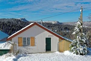 ein kleines weißes Haus im Schnee mit einem Baum in der Unterkunft Gîte du Bief de la Chaille in Les Rousses
