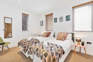 two beds in a room with white walls and windows at Seaview Heights - By My Getaways in Brighton & Hove