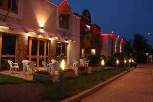 une rue avec des chaises et des lumières devant un bâtiment dans l'établissement Best Hotel Sancé - Mâcon, à Mâcon