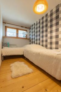 1 dormitorio con 2 camas y pared a cuadros en Apartament Lisowski CENTRUM, en Zakopane