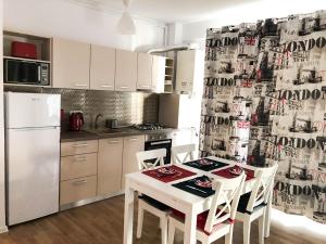 a kitchen with a white table and chairs and a refrigerator at London 18 Apartment in Mamaia Sat/Năvodari