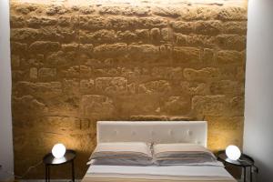 a bedroom with a brick wall and a white bed at B&B Kolymbetra in Agrigento