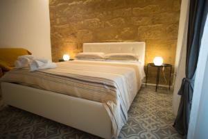 a bedroom with a white bed with a stone wall at B&B Kolymbetra in Agrigento