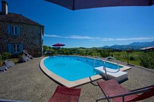 a swimming pool with two chairs next to a house at Mountain Vacances - Maison Rachou in Lanne-en-Barétous 