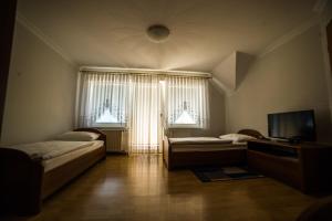 a room with two beds and a tv and two windows at Gostišče Pri Dveh Petelinih in Bled