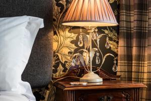 a lamp on a table next to a bed at Glenegedale House in Kintra