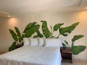 1 dormitorio con 1 cama con grandes hojas verdes en la pared en Hotel CaféNaranja Xilitla, en Xilitla