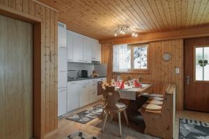 - une cuisine avec des placards blancs, une table et des chaises dans l'établissement Ferienwohnung Sunnehöckli, à Sattel