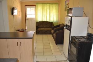 a kitchen with a refrigerator and a living room at Heloise Home Stay in Oudtshoorn