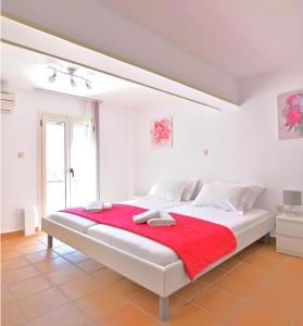 a white bedroom with a large bed with a red blanket at Villa Ela Ferienappartements in Metaxáta
