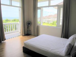 a bedroom with a bed and two large windows at Villa Panda at Sea Links Golf Resort in Mui Ne +39 photos