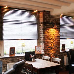 een eetkamer met een tafel en een bakstenen muur bij Ye Olde Nags Head in Castleton