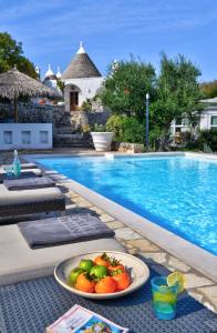 - une assiette de fruits sur une table à côté de la piscine dans l'établissement B&B Trullo Barbagiullo, à Cisternino