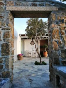 uma parede de pedra aberta com uma árvore num pátio em Kipos Villas & Suites em Míconos