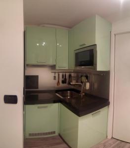 eine Küche mit grünen Schränken, einer Spüle und einer Mikrowelle in der Unterkunft Heart of Brera in Mailand