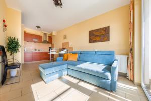 a blue couch in a living room with a kitchen at Apartamenty Sun & Snow Bursztynowy in Władysławowo