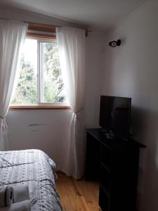 una camera da letto con un letto, una televisione e una finestra di departamento valdivia a Valdivia