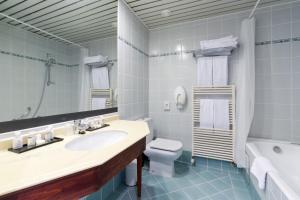 a bathroom with a sink and a toilet and a tub at Thermae Palace in Ostend