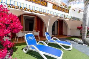 two blue chairs on a lawn in front of a house at Parque Santiago III Official in Playa de las Americas