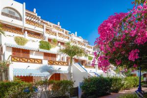 ein weißes Gebäude mit rosa Blumen davor in der Unterkunft Parque Santiago III Official in Playa de las Americas