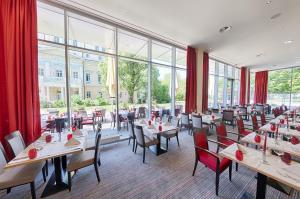 um restaurante com mesas e cadeiras e janelas grandes em Welcome Hotel Darmstadt City Center em Darmstadt