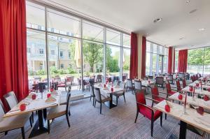 ein Restaurant mit Tischen und Stühlen und großen Fenstern in der Unterkunft Welcome Hotel Darmstadt City Center in Darmstadt