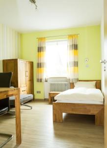 a bedroom with a bed and a desk and a window at Gästehaus Loehnert GmbH in Coburg