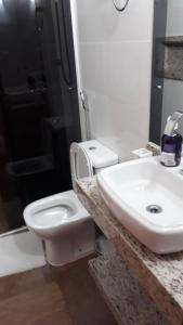 een badkamer met een wit toilet en een wastafel bij Pousada da Tia Cida in Capitólio