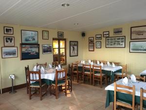 un comedor con mesas, sillas y cuadros en las paredes en hotel la trainera en Pedreña