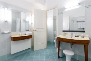 een badkamer met een wastafel, een toilet en een spiegel bij Thermae Palace in Oostende
