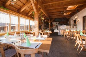 restauracja z drewnianymi stołami, krzesłami i oknami w obiekcie Hotel Restaurant Schönau w mieście Wildhaus