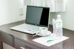 a laptop computer on a desk with a cup and a water bottle at Chiapas Hotel Express in Tuxtla Gutiérrez
