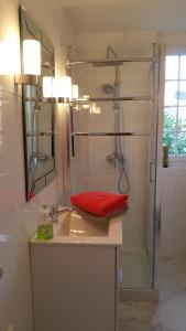 La salle de bains est pourvue d'une douche et d'un lavabo avec une serviette rouge. dans l'établissement Moulin du Hamelet, à Saint-Aubin-sur-Scie