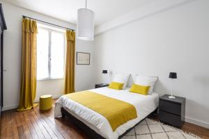 - une chambre avec un grand lit et des oreillers jaunes dans l'établissement LE RECIT by Cocoonr, à Rennes