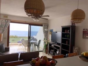 Una sala de estar con un sofá y una mesa con televisión. en Appartment Teneriffa Tamara Anlage, en Santiago del Teide