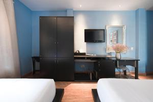 a bedroom with a desk and a cabinet with a television at A&EM - The Petit Hotel in Ho Chi Minh City