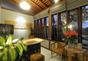 a room with a table and some plants and windows at Uma Karan in Seminyak