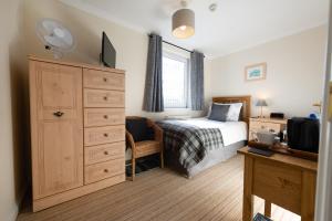 Schlafzimmer mit einem Bett und einer Kommode mit einem TV in der Unterkunft Blue Swallow in Penrith