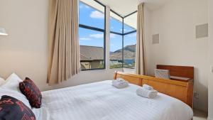 um quarto com uma grande janela e uma cama com toalhas em The Haddens em Queenstown