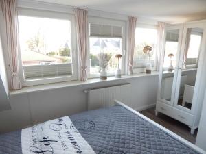 sypialnia z łóżkiem w pokoju z oknami w obiekcie Haus SMEELWAI 21 w mieście Westerland